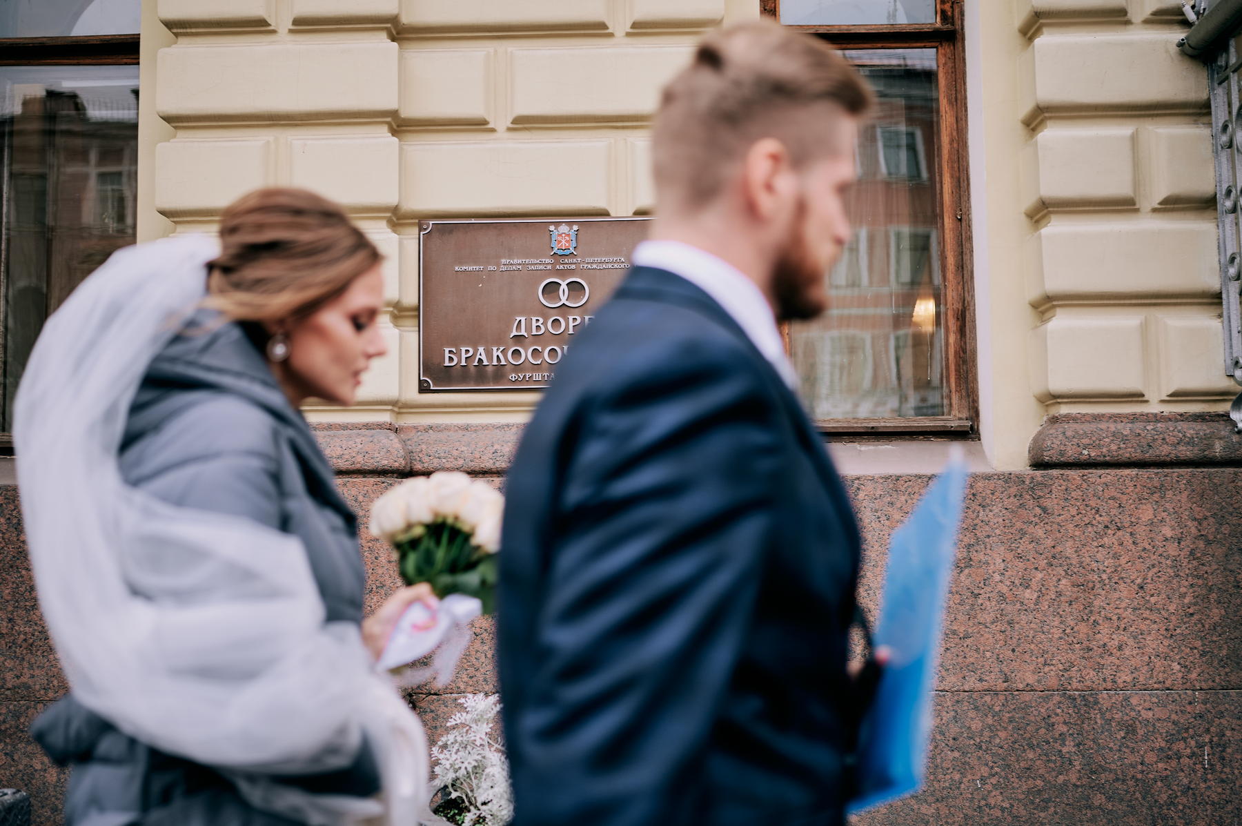 Молодожёны проходят мимо вывески дворца бракосочетания