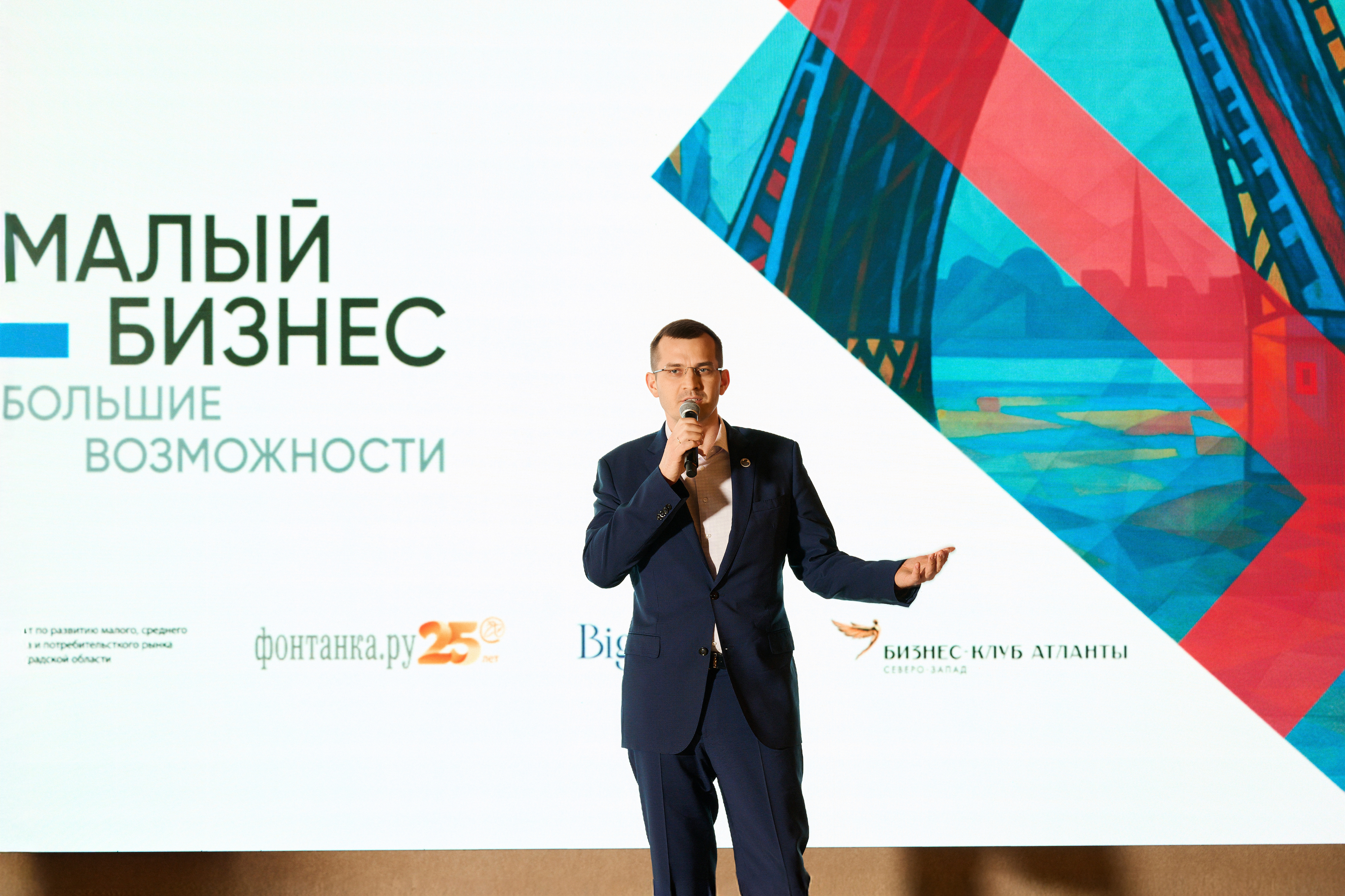 Ведущий с микрофоном на сцене делового мероприятия