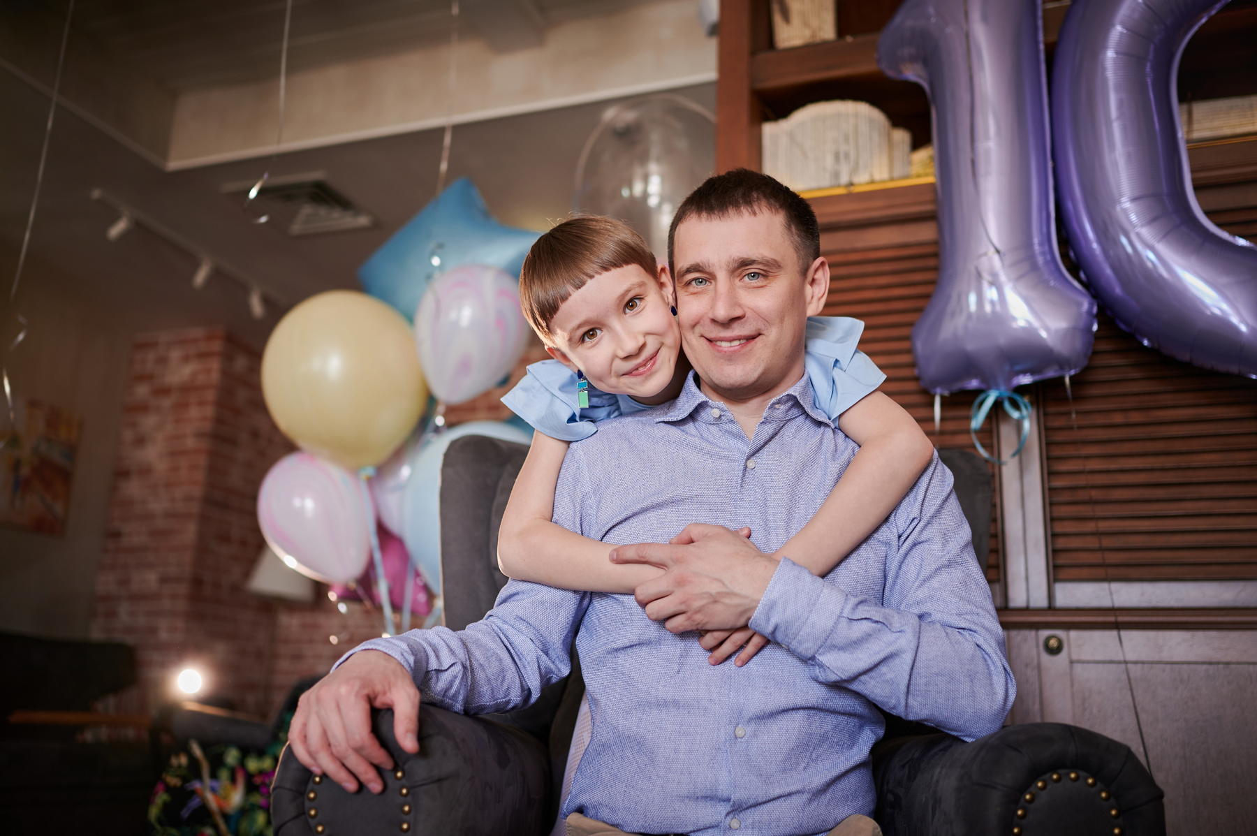Дочь в голубом платье обнимает папу за шею