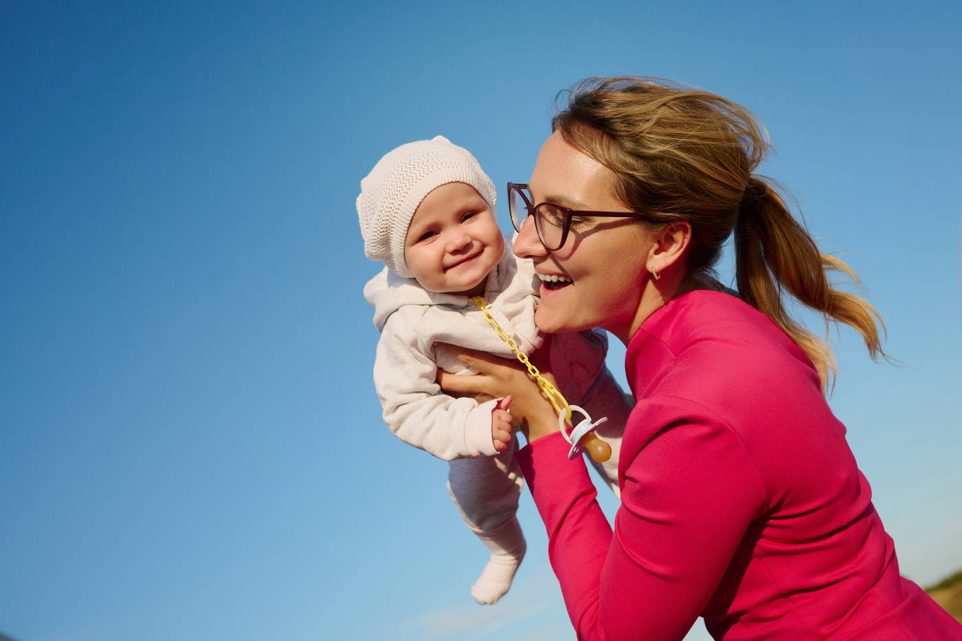 Улыбающаяся гостья в розовом платье держит малыша